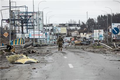 02.04.2022, Ukraine, Butscha: Ein ukrainischer Soldat geht entlang von Leichen auf einer zerstörten Straße.
