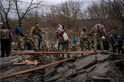 05.03.2022: Ukrainische Soldaten helfen einer fliehenden Familie bei der Überquerung des Flusses Irpin in den Außenbezirken von Kiew
