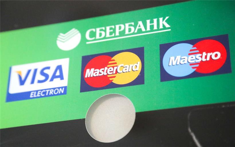 06.03.2022, Russland, St. Petersburg: Die Logos von Visa, Mastercard und Maestro sind auf einem Geldautomaten der Sberbank zu sehen
