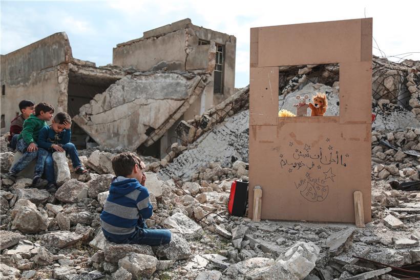 2019, Syrien, Saraqib: Puppenspieler Walid Rashed führt für syrische Kinder inmitten von Trümmern beschädigter Gebäude einen Marionettenauftritt vor.
