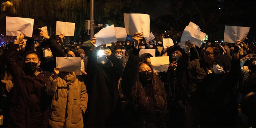 27.11.2022, China, Peking: Demonstranten halten leere Papiere hoch, während sie protestieren
