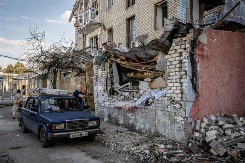 29.07.2022, Ukraine, Slowjansk: Ein Mann raucht vor seinem Auto, während er die Ruinen von Wohngebäuden betrachtet, nachdem russische Artilleriegeschosse das Stadtzentrum getroffen haben
