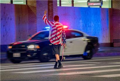 A protester holds up a peace sign as police drive down Hollywood Boulevard after curfew during a demonstration over the death of George Floyd while in Minneapolis Police custody, in Los Angeles, California, June 2, 2020. 

