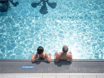 Zwei Menschen am Beckenrand eines Schwimmbads