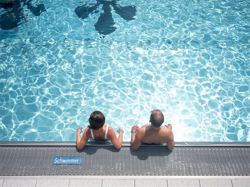 Zwei Menschen am Beckenrand eines Schwimmbads