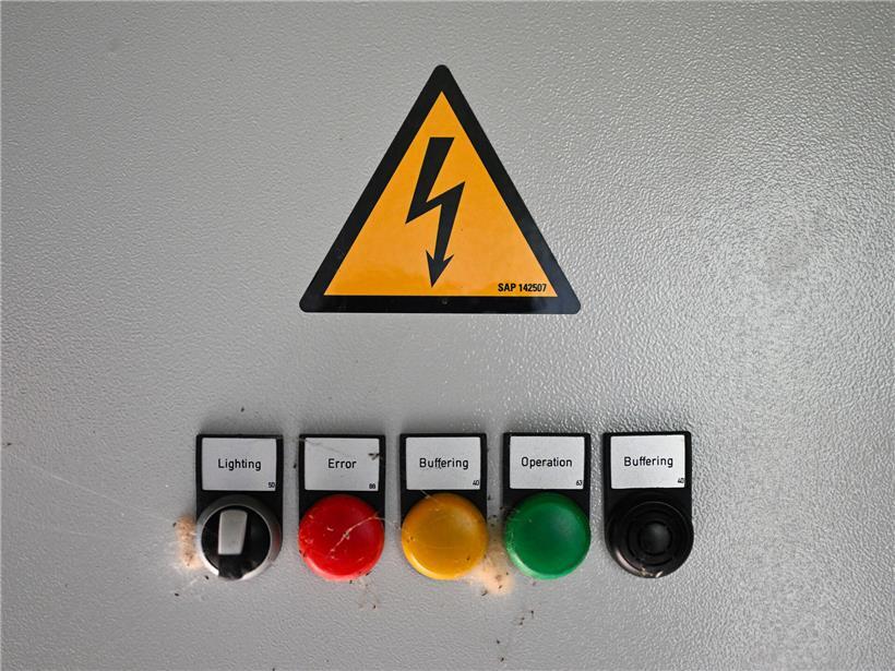 Warnhinweis "Achtung Strom" in leuchtendem Gelb auf schwarzem Hintergrund im Inneren eines elektrischen Geräts