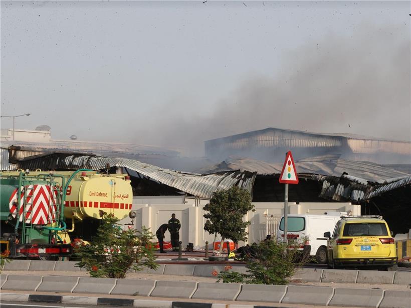 Feuerwehrleute löschen Brand vor beschädigtem Lagerhaus in Al Rayyan, Katar nach iranischem Angriff im Industriegebiet