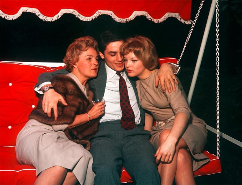 Alain Delon sitzt auf einer Hollywoodschaukel zwischen seiner damaligen Verlobten Romy Schneider (r) und deren Mutter Magda Schneider (l) 
