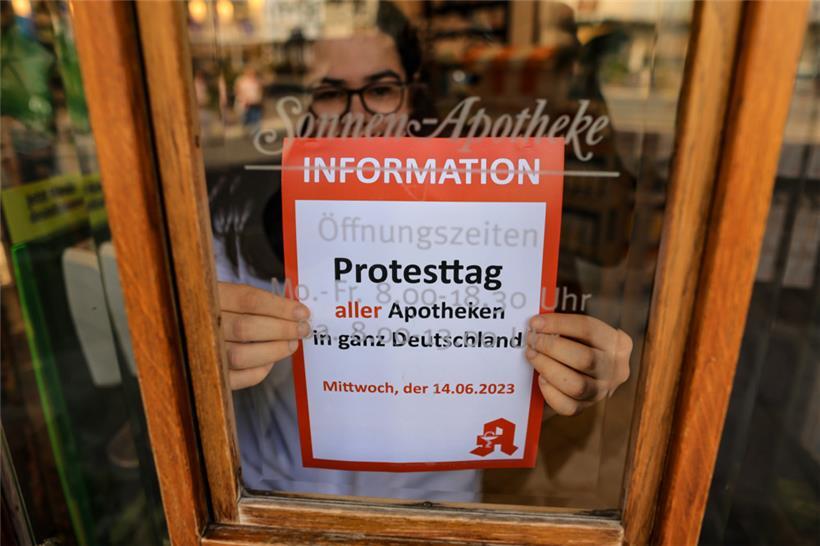 Alle müssen draußen bleiben: Die Mitarbeiterin einer Apotheke klebt einen Hinweis auf den Schließtag an die Tür der Sonnen-Apotheke in Leipzig
