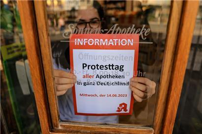 Alle müssen draußen bleiben: Die Mitarbeiterin einer Apotheke klebt einen Hinweis auf den Schließtag an die Tür der Sonnen-Apotheke in Leipzig
