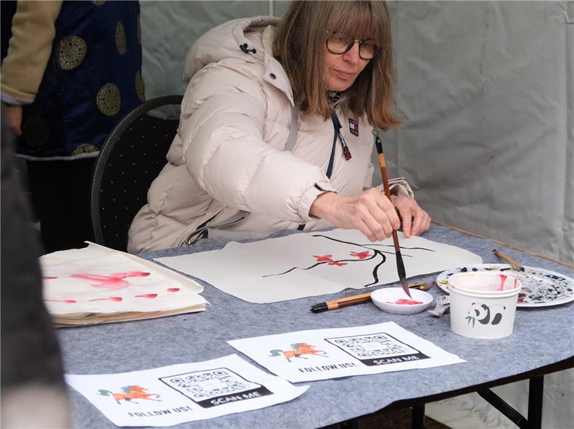 Besucher am Stand des Konfuzius-Instituts üben chinesische Kalligrafie und traditionelle Malerei aus