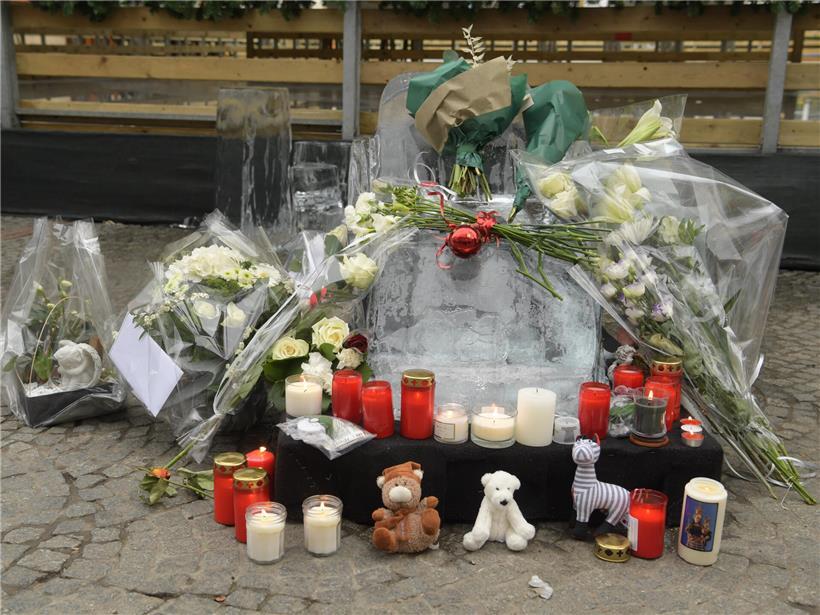 Blumen, Kerzen und Stofftiere an den Überresten einer geschmolzenen Eisfigur als Gedenkstätte nach Unglück