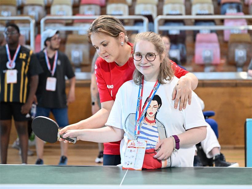 Sportlerinnen und Sportler spielen mit Freude Tischtennis an der Tischtennis-Platte während eines Turniers