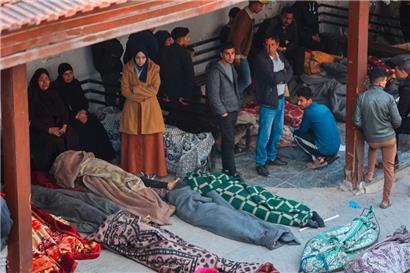 Angehörige stehen neben den in Decken eingewickelten Leichen auf dem Gelände des Al-Mamdani-Krankenhauses in Gaza-Stadt
