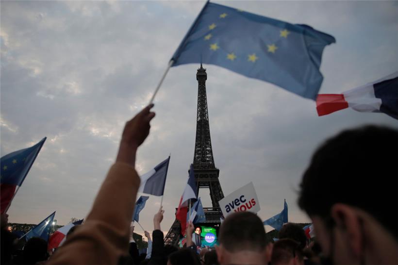 Anhänger des französischen Präsidenten Emmanuel Macron feiern am Eiffelturm mit Landesflaggen und Europafahnen
