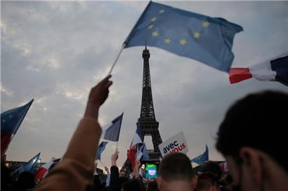 Anhänger des französischen Präsidenten Emmanuel Macron feiern am Eiffelturm mit Landesflaggen und Europafahnen
