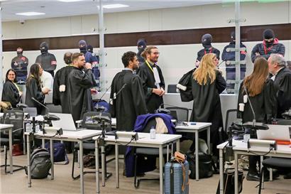 Anwälte sprechen mit ihren Mandanten durch einen Glaskasten 
