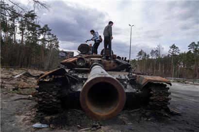 Anwohner stehen auf einem russischen Panzer, der bei Kämpfen zwischen russischen und ukrainischen Streitkräften in einem Außenbezirk von Kiew beschädigt wurde
