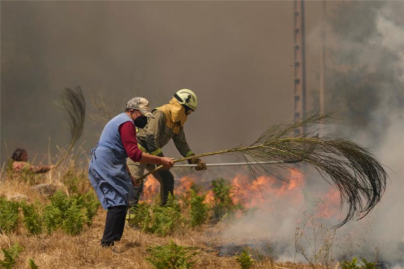 Anwohner und Feuerwehrleute bekämpfen ein Feuer bei Rebordondo in der Nähe von Ourense
