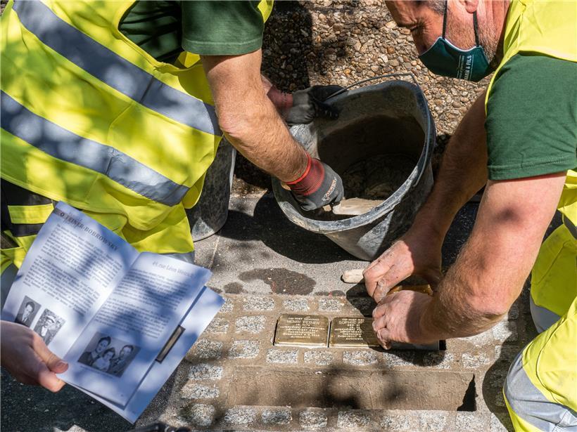 Arbeiter bringen die Stolpersteine auf dem Bürgersteig an. Während der Zeremonie wird die Geschichte der Menschen erzählt, die hier wohnten – und dann von den Nazis ermordet wurden. 
