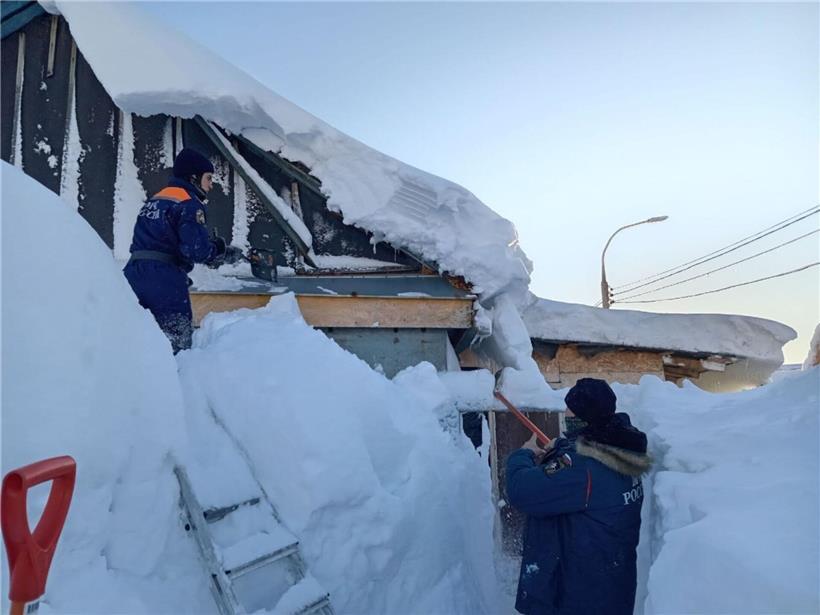Arbeiter räumen Schnee sicher vom Dach eines Gebäudes bei winterlichen Bedingungen