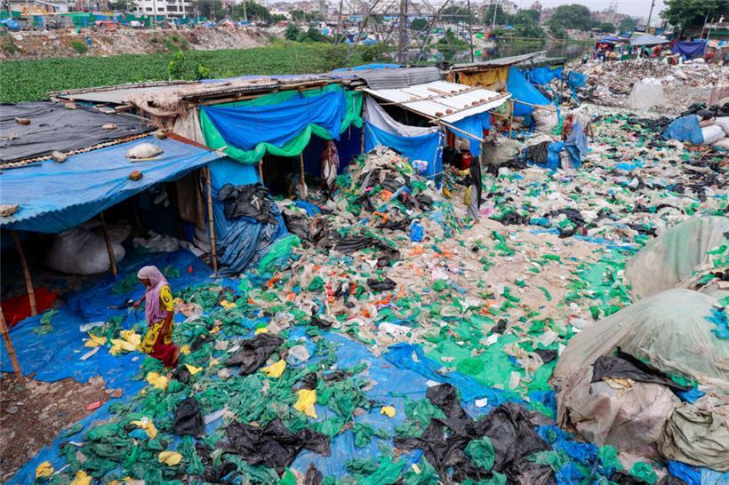 Arbeiterinnen sortieren und trocknen gebrauchte Plastiktüten, nachdem sie sie in einer informellen Recyclinganlage in Dhaka, Bangladesch, gewaschen haben
