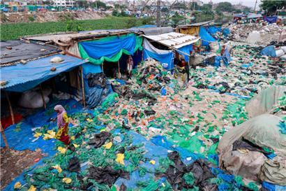 Arbeiterinnen sortieren und trocknen gebrauchte Plastiktüten, nachdem sie sie in einer informellen Recyclinganlage in Dhaka, Bangladesch, gewaschen haben
