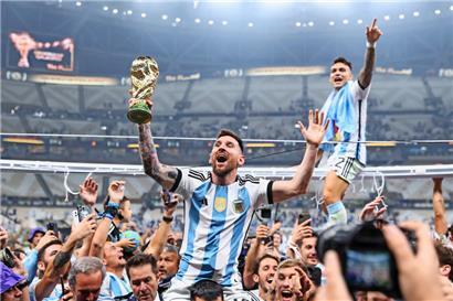 Argentiniens Lionel Messi und Lautaro Martínez lassen sich mit dem Weltmeisterpokal feiern 
