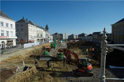 Arlon verändert sich. Die Umgestaltung des place Léopold ist eingebettet in weitere Modernisierungen und Renovierungen an den Straßen rundherum. Spielraum für die Investitionen bieten die rund 8,7 Millionen Euro jährlichen Einnahmen aus dem „Fonds Juncker-Reynders“. Das Gesamtbudget der Stadt beträgt rund 58 Millionen Euro. Weiter links liegt die Fußgängerzone mit vielen kleinen Geschäften. 
