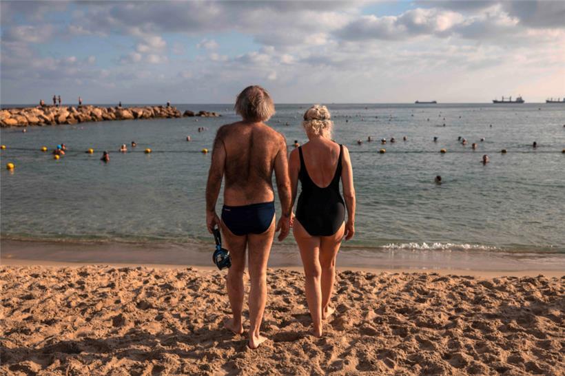 Auf der anderen Seite: Ein Mann und eine Frau schauen am Strand von Haifa in Israel auf das Mittelmeer

