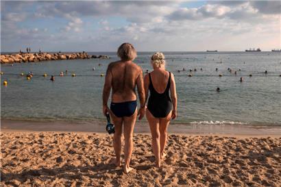 Auf der anderen Seite: Ein Mann und eine Frau schauen am Strand von Haifa in Israel auf das Mittelmeer
