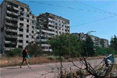 Auf diesem Foto, das am 15. Juli 2025 vom Pressedienst der 65. Mechanisierten Brigade der ukrainischen Streitkräfte aufgenommen und veröffentlicht wurde, ist ein Mann in Orikhiv in der Region Saporischschja inmitten der russischen Invasion in der Ukraine zu sehen, wie er in der Nähe von beschädigten Gebäuden und Anti-Drohnen-Netzen entlanggeht
