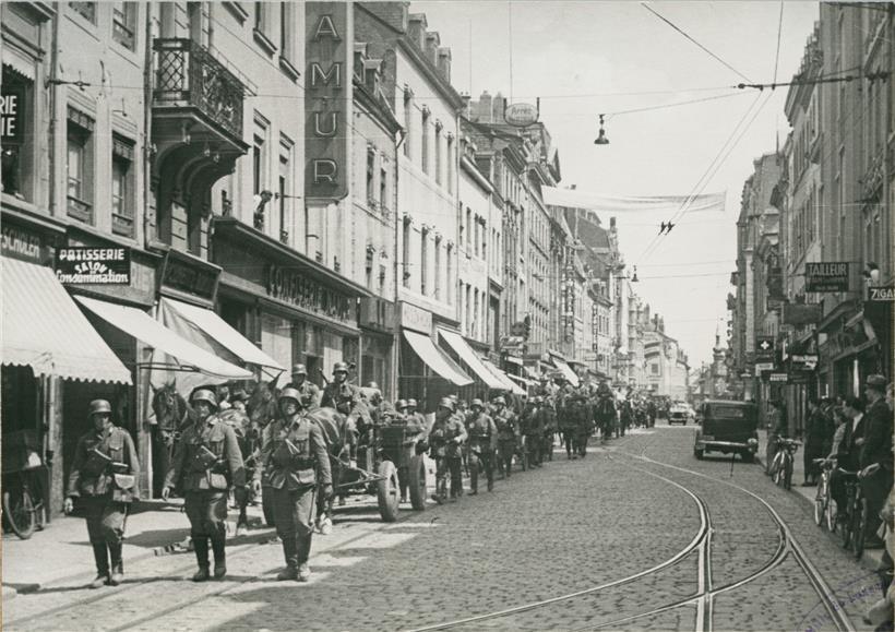 Aufmarsch der deutschen Truppen in der Grand’rue der Hauptstadt am 10. Mai 1940. Das schmale Haus links neben „Namur“ ist die Nr. 62.
