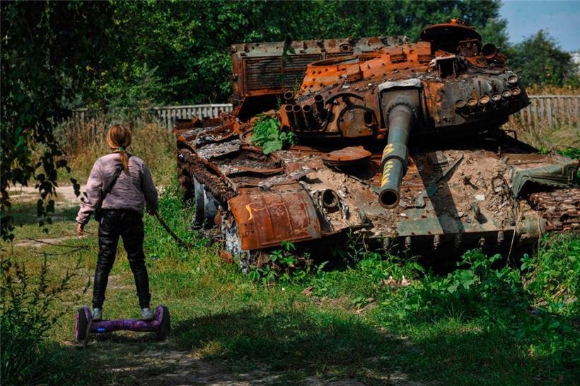 Aufwachsen im Krieg: Ein Teenager fährt nahe Tschernihiw auf einem Hoverboard an einem zerstörten russischen Panzer vorbei
