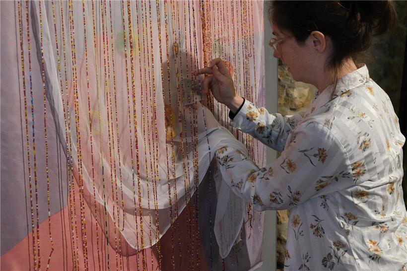 Aurélie fädelt bunte Perlen für handgefertigtes Kunstwerk in kreativem Schmuckdesign ein