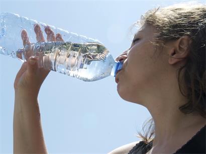 Glas Wasser auf Holztisch bei sonnigem Wetter – wichtiges Trinken bei hohen Temperaturen