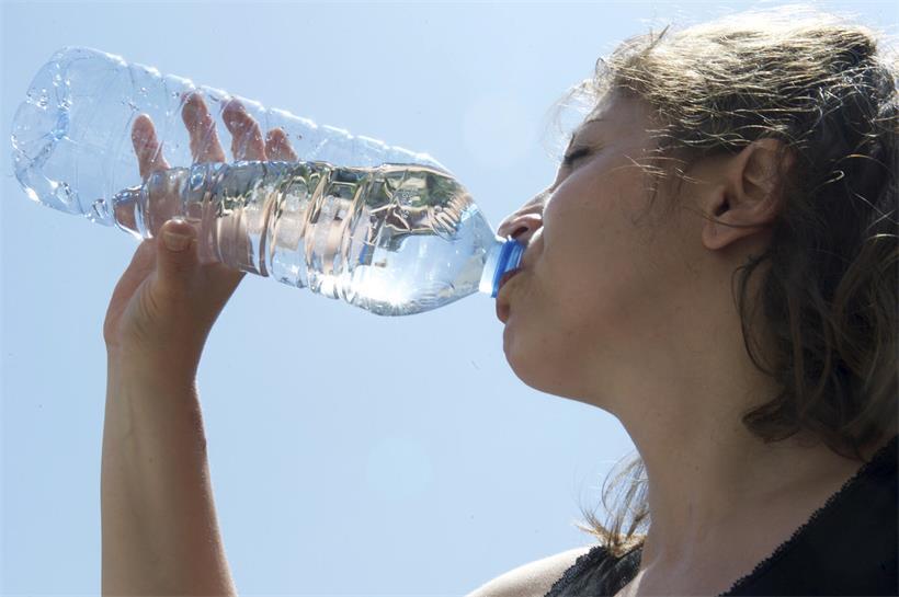 Glas Wasser auf Holztisch bei sonnigem Wetter – wichtiges Trinken bei hohen Temperaturen
