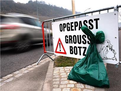 Autofahrer fahren vorsichtig an Müll sammelnden Bürgern entlang auf einer belebten Straße