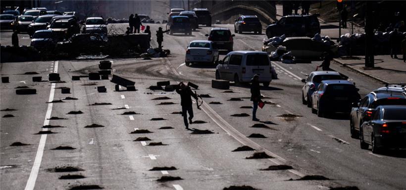 Autos werden an einer Straßensperre gestoppt, die von Zivilschützern an einer Straße ins Zentrum von Kiew errichtet wurde
