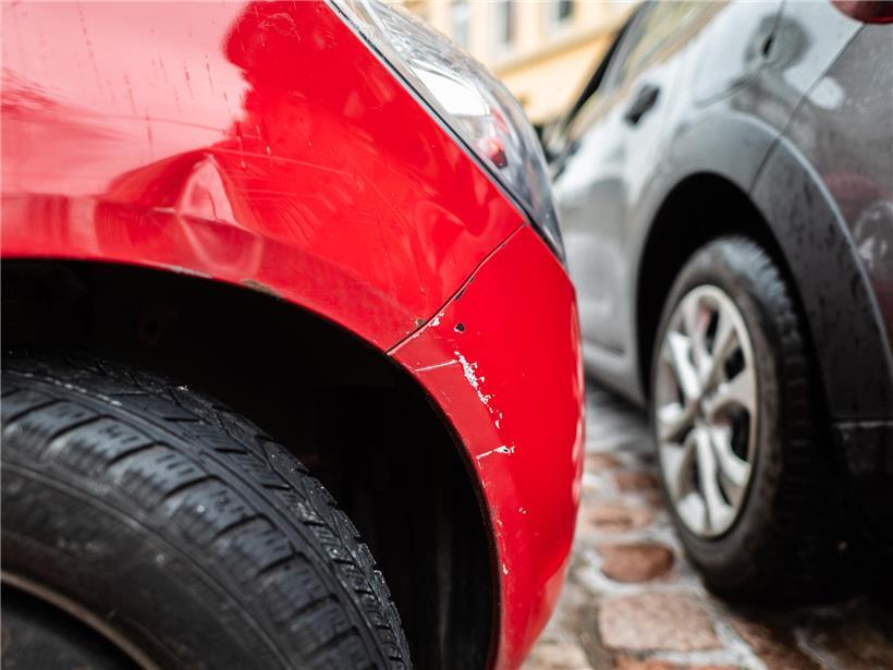 Beschädigtes Auto mit sichtbaren Beulen und Kratzern nach Unfall, Nahaufnahme der Schadstelle am Fahrzeug
