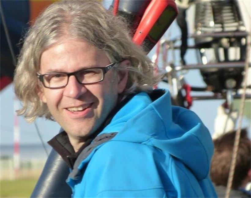 Weltrekord-Ballon landet nach Atlantik-Überquerung in Luxemburg Ballonfahrer Claude Weber in bunter Heißluftballon-Kabine über malerischer Landschaft bei klarem Himmel