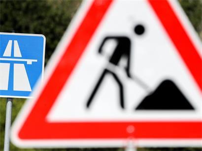 Baustellenarbeiter bei frühzeitigen Arbeiten auf einer städtischen Baustelle mit Absperrungen und Baumaschinen