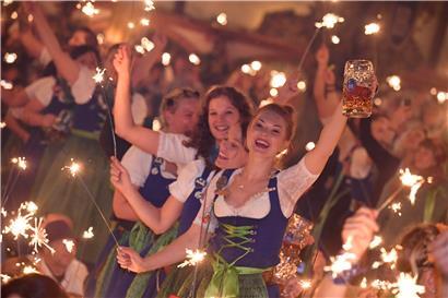 Bedienungen stehen im Hofbräu-Zelt beim traditionellen Kehraus auf den Tischen, halten dabei Wunderkerzen in den Händen und feiern damit das Ende der harten Arbeit auf der Wiesn. 
