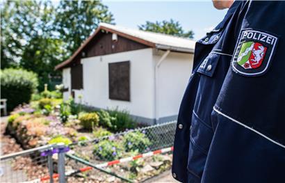 Bei den Ermittlungen nach schwerem sexuellem Missbrauch von Kindern steht ein Polizeibeamter vor einer Gartenlaube, die als mutmaßlicher Tatort gilt
