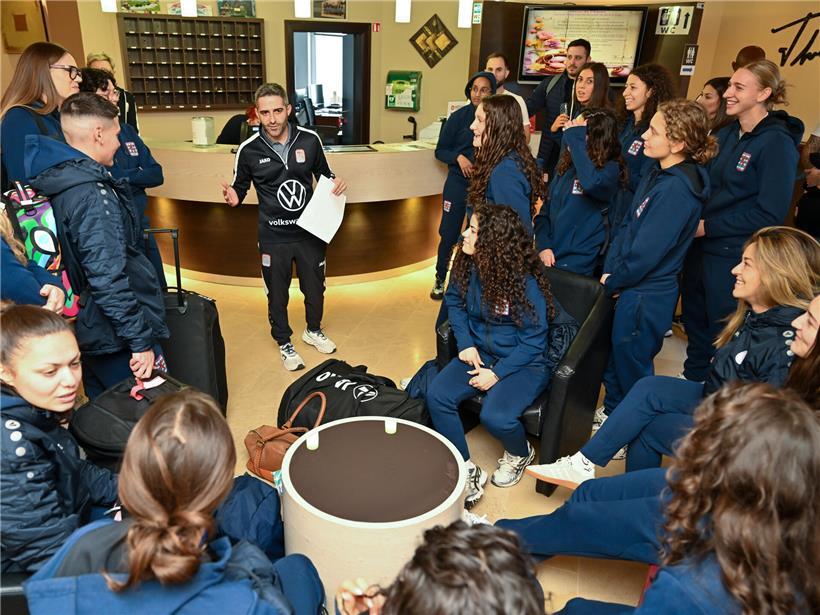 Hotel-Ankunft mit Coach-Briefing im Eingangsbereich, Gäste hören aufmerksam zu, Vorbereitung auf Team-Event