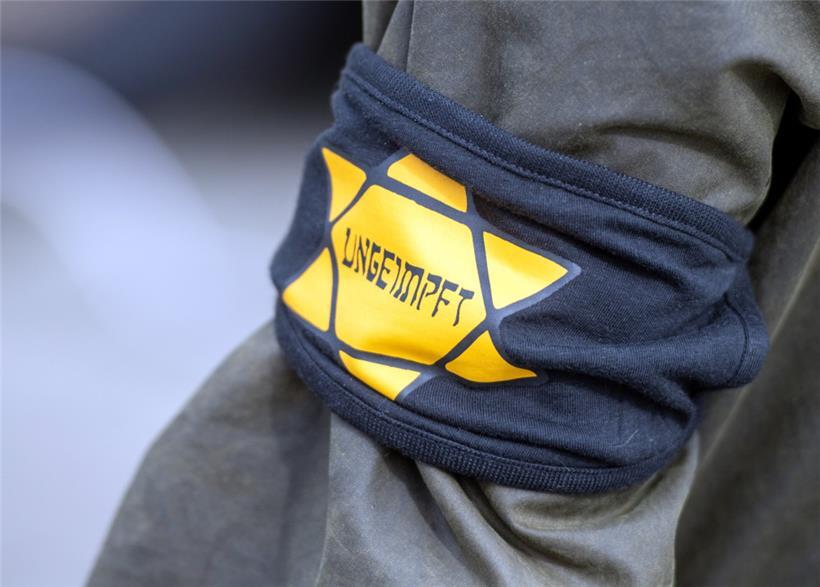 Bei einer Demonstration gegen die Einschränkungen durch die Pandemie-Maßnahmen der Bundesregierung trägt ein Teilnehmer eine Armbinde mit einem gelben Stern, der an einen Judenstern erinnern soll, mit der Aufschrift „Ungeimpft“ 
