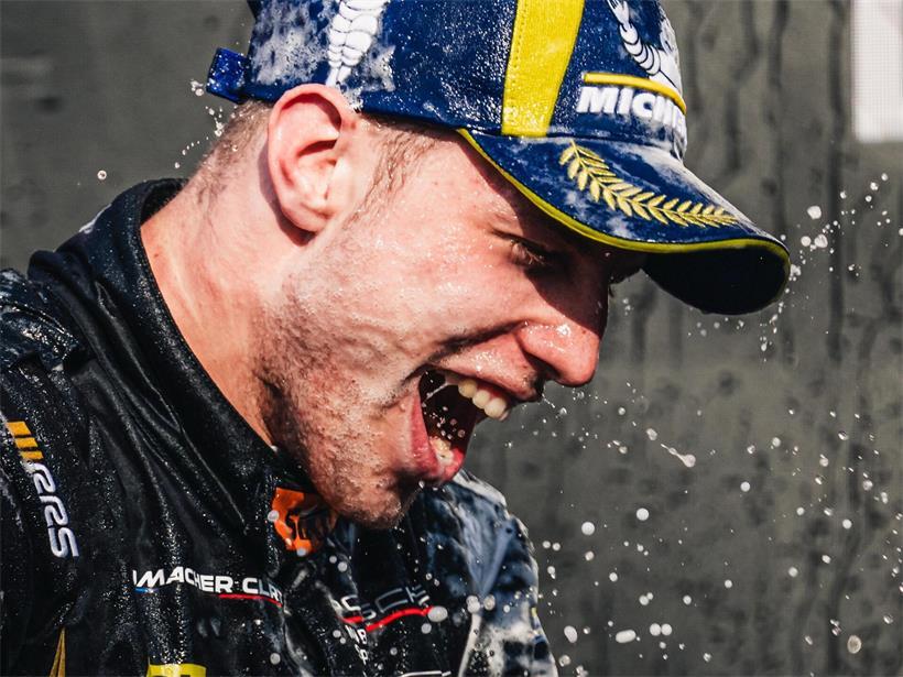 Chester Kieffer auf dem Podium beim Porsche Carrera Cup mit Rennanzug und Pokal in der Hand