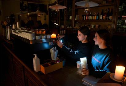 Bereits vor den massiven russischen Angriffen auf die ukrainische Stromversorgung haben sich diese Kaffeehausbetreiber in der westukrainischen Stadt Lwiw teilweise auf alternative Beleuchtungsquellen verlegt
