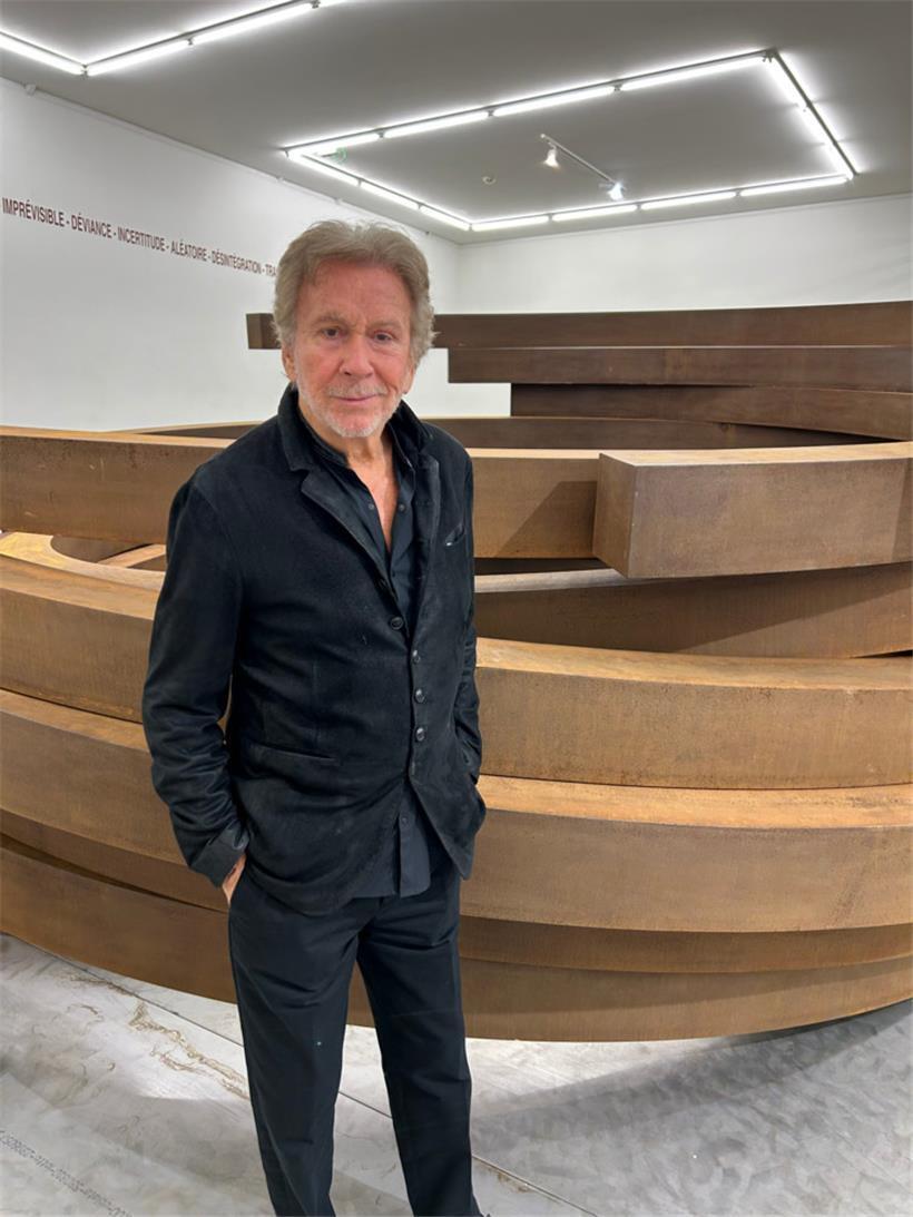 Bernar Venet posiert vor seiner Großskulptur, die er mit einer Performance verändert hat
