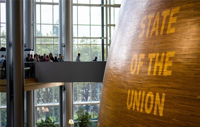 Besucher gehen über eine Brücke in den sogenannten „Hémicycle“, den Kern des Europäischen Parlaments in Straßburg, während dieser von außen mit dem Schriftzug „State of the Union“ angestrahlt wird
